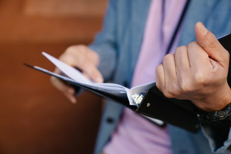 Person flipping through documents in a binder, showcasing organization and focus.