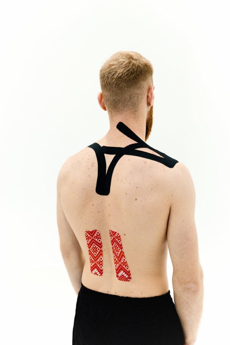 Man standing with kinesio tape for muscle support on a white background.