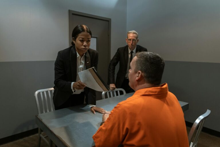 A tense interrogation scene in a prison room with officials and a prisoner.