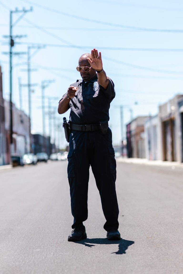 Police officer in uniform gesturing stop in a city street during the day.