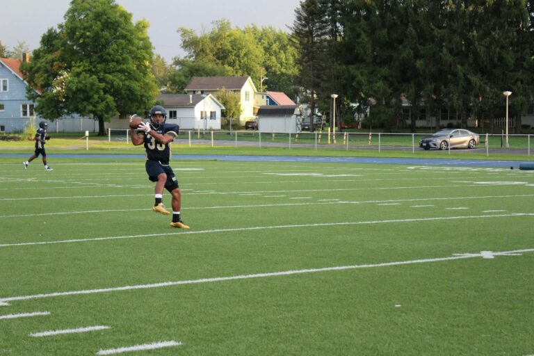 Football player in action catching a ball during practice on a sunny day.