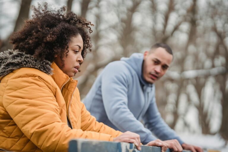Couple preparing for winter workout in the park, dressed in warm outerwear.