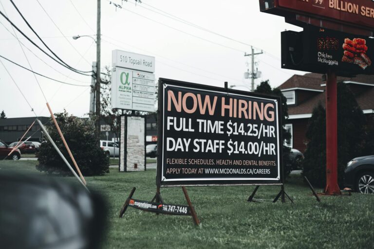 Outdoor hiring sign advertising restaurant job openings with competitive wages and benefits.