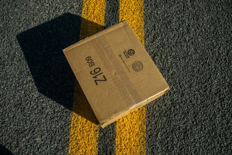 A cardboard box on road asphalt marked with yellow lines, captured in a unique angle.