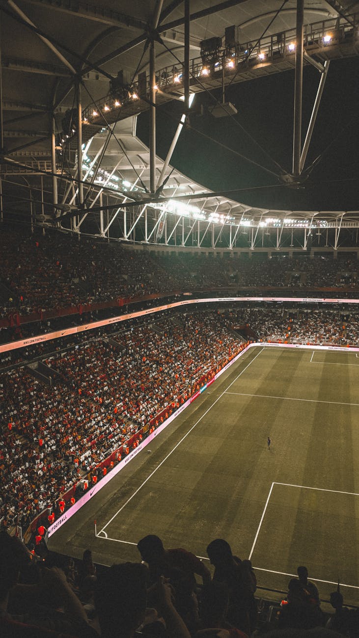 A vibrant night soccer match with a full audience in an illuminated stadium.