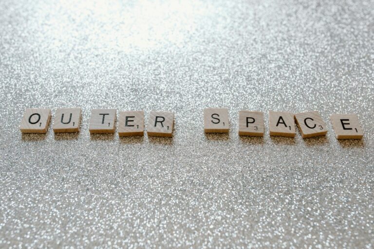 Scrabble tiles spelling 'Outer Space' on glittery surface, creative concept image.