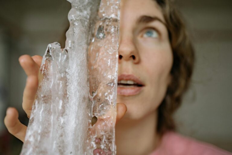A woman holding an ice icicle indoors, showcasing selective focus on textures.