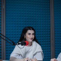 Woman recording a podcast in a soundproof studio, using a microphone.