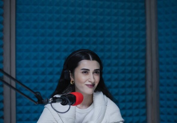 Woman recording a podcast in a soundproof studio, using a microphone.