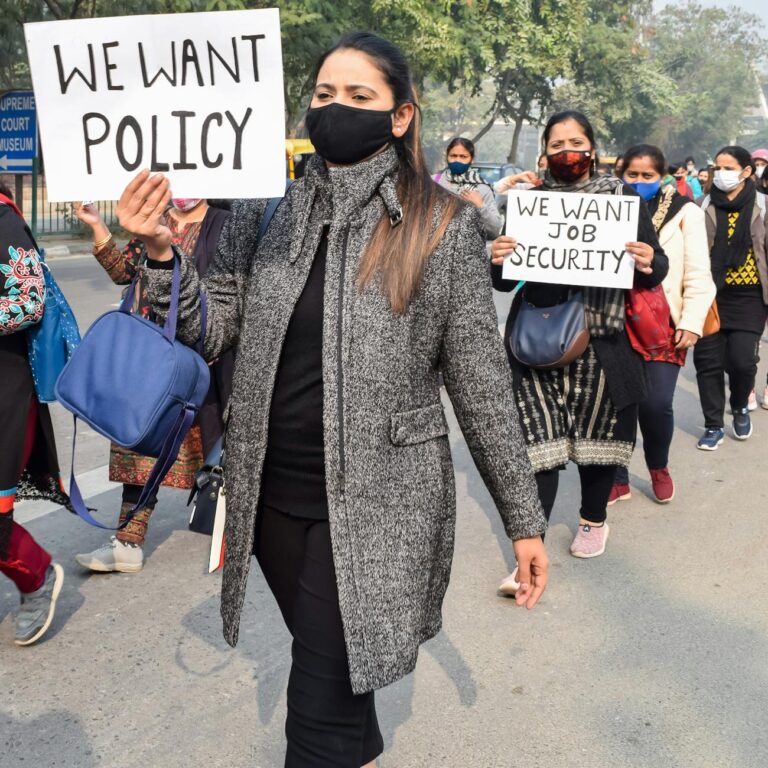 Women demonstrating for policy change and job security during a street protest.