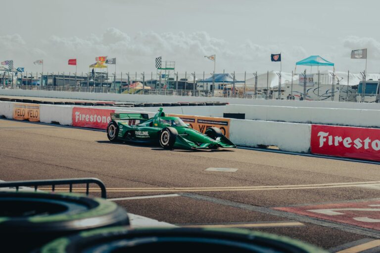 Green IndyCar racing on the track at St. Petersburg, Florida under a clear sky.