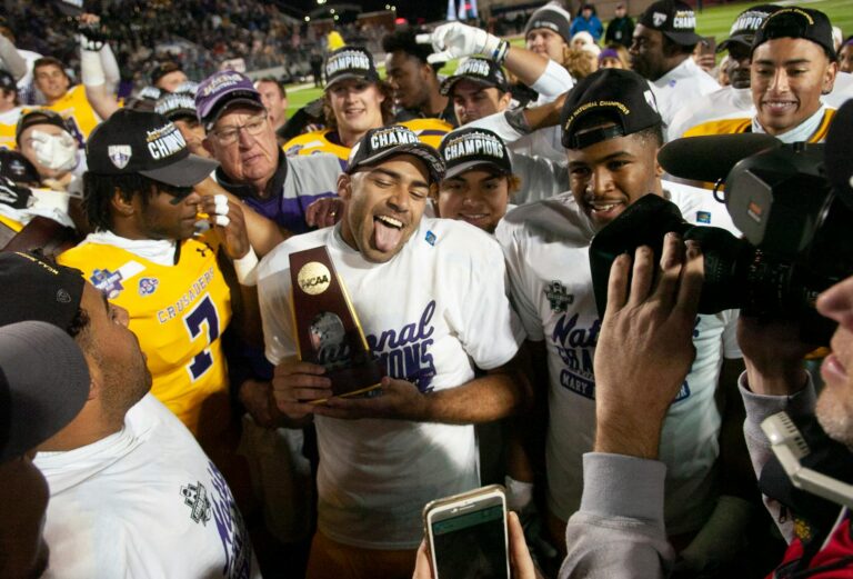 Football team celebrating their national championship victory with trophy and media.