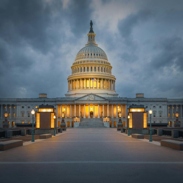 Stunning view of the illuminated United States Capitol building against dramatic clouds in Washington, DC at dusk.