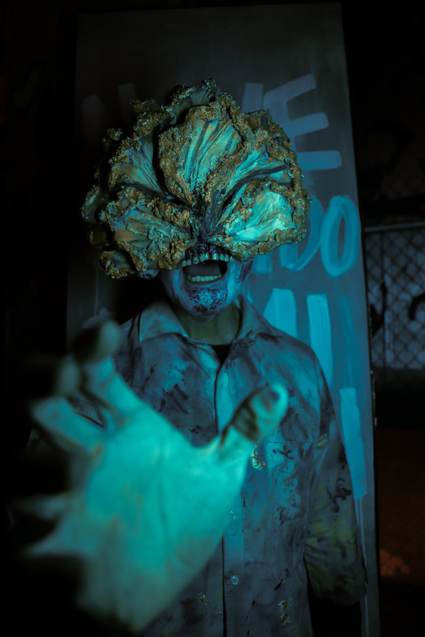 A mysterious figure stands in neon light wearing an artistic and surreal mask, creating an eerie atmosphere.