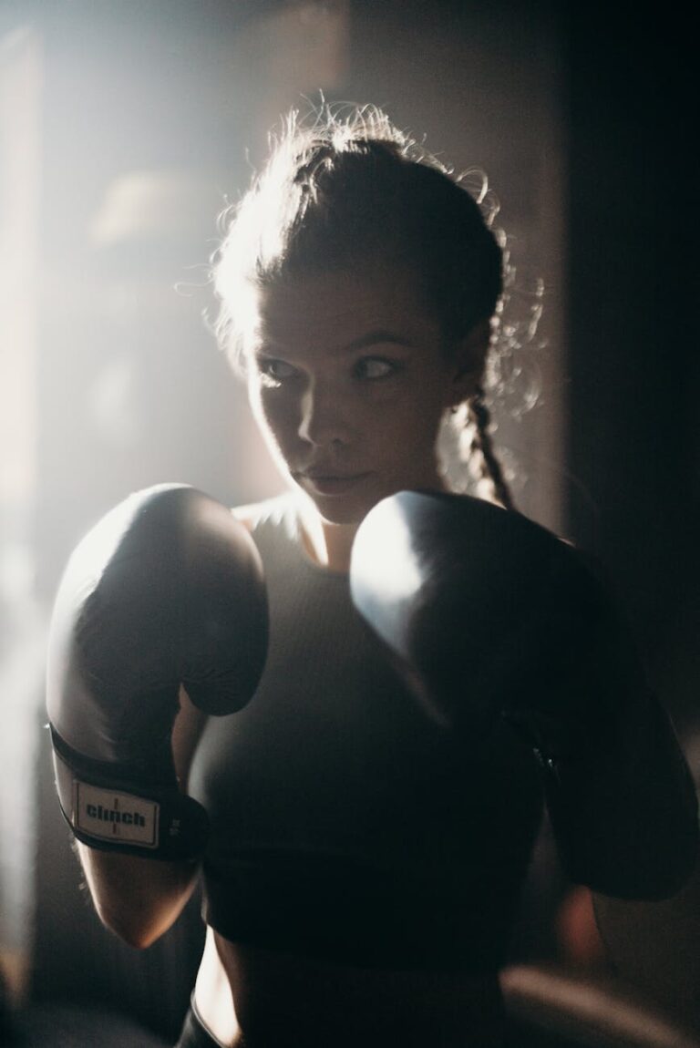 Determined female boxer in training, wearing gloves, preparing for a sparring session indoors.
